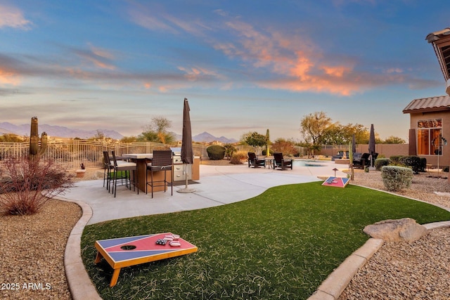 yard at dusk with a bar, a fenced in pool, and a patio area