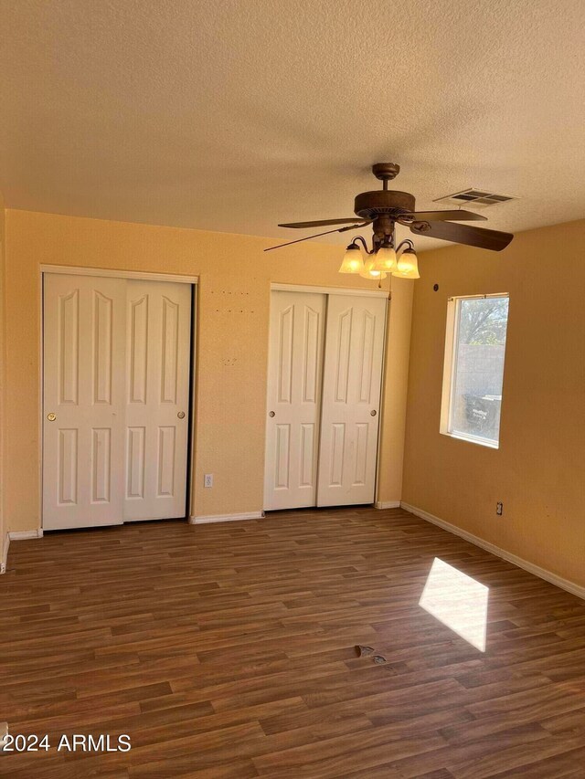 unfurnished bedroom with a textured ceiling, ceiling fan, and dark hardwood / wood-style floors