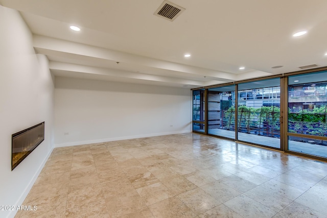 spare room featuring baseboards, floor to ceiling windows, visible vents, and recessed lighting