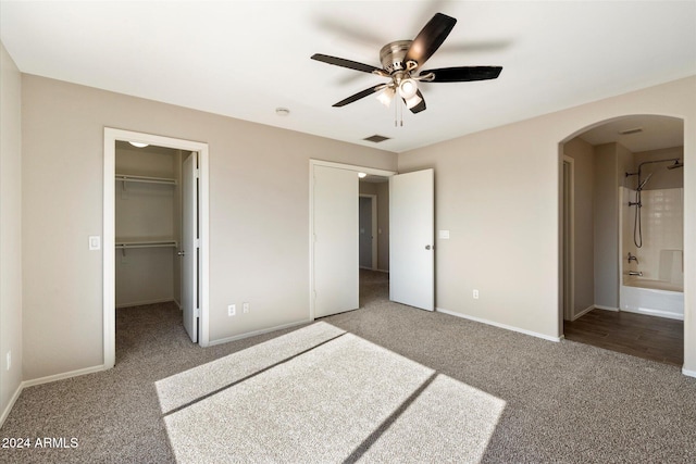 unfurnished bedroom with connected bathroom, a spacious closet, ceiling fan, carpet floors, and a closet