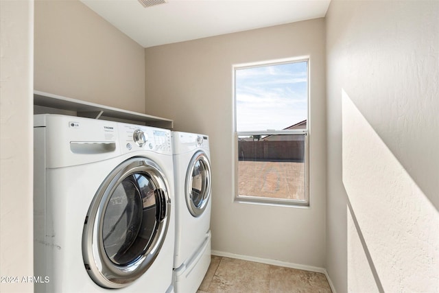 clothes washing area with washer and dryer and light tile patterned floors