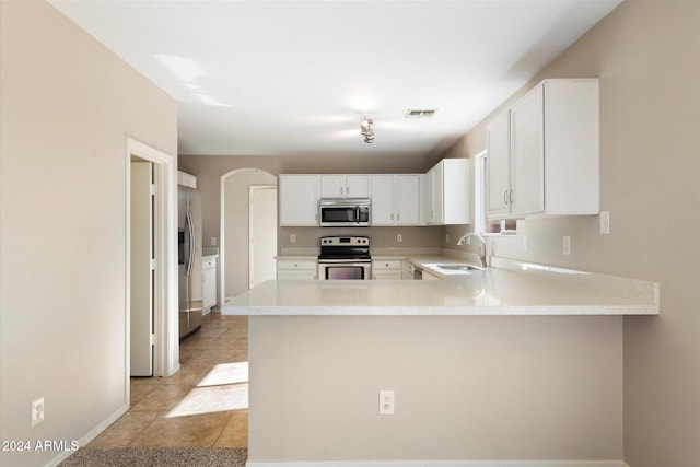 kitchen featuring sink, light tile patterned flooring, kitchen peninsula, white cabinets, and appliances with stainless steel finishes