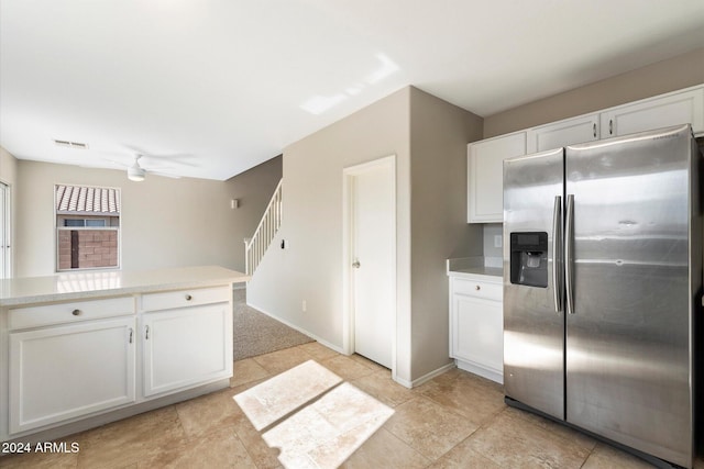 kitchen with stainless steel fridge, white cabinetry, and ceiling fan