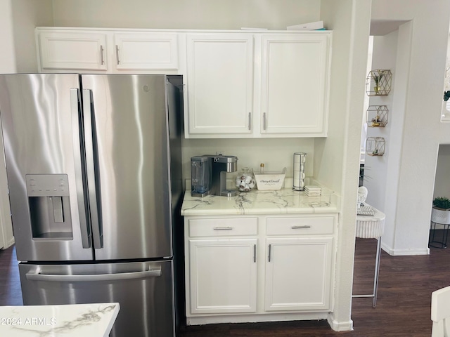 kitchen featuring light stone countertops, white cabinets, dark hardwood / wood-style floors, and stainless steel fridge