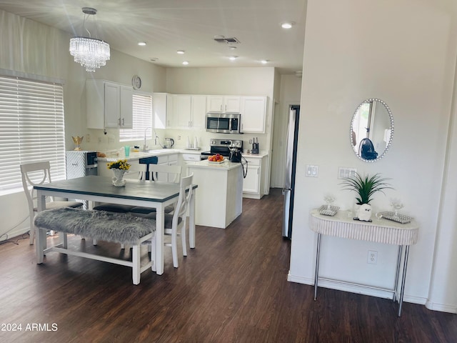 kitchen with sink, decorative light fixtures, dark wood-type flooring, white cabinetry, and appliances with stainless steel finishes