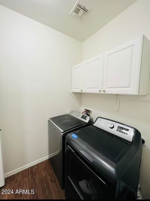 washroom featuring cabinets, washing machine and clothes dryer, and dark hardwood / wood-style flooring