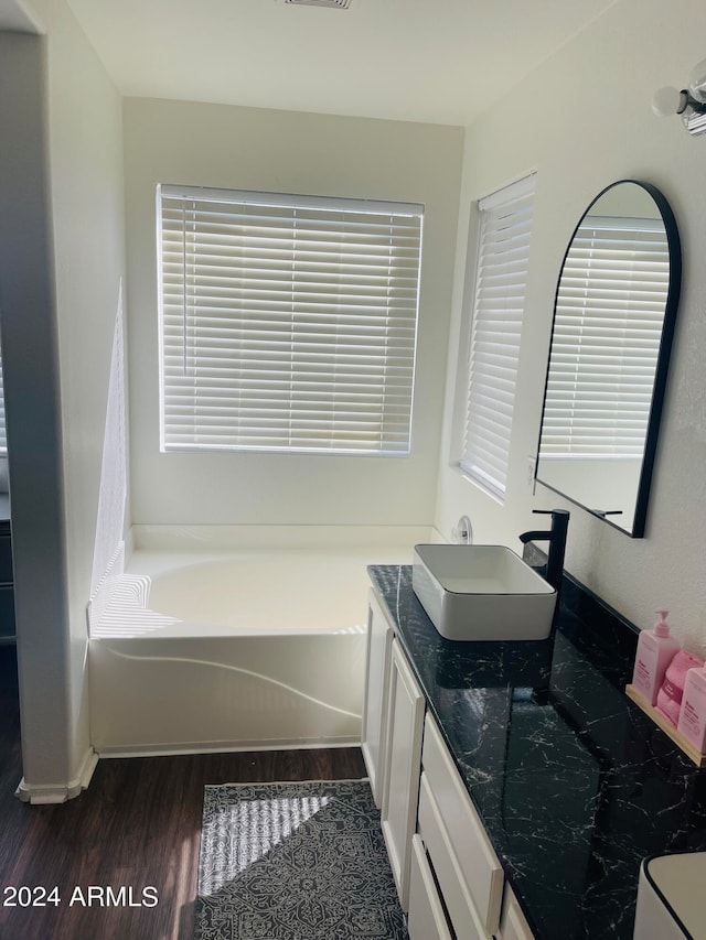 bathroom with a tub to relax in, vanity, and hardwood / wood-style flooring