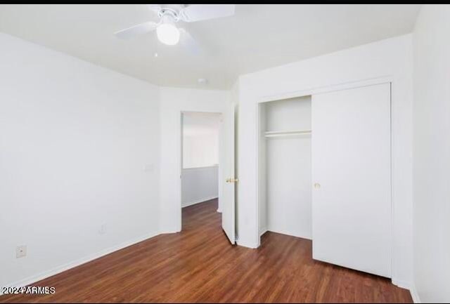 unfurnished bedroom featuring dark hardwood / wood-style floors, ceiling fan, and a closet