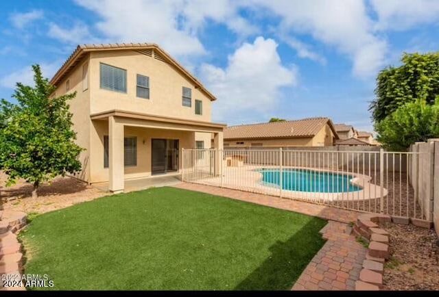 rear view of house featuring a fenced in pool, a patio area, and a yard