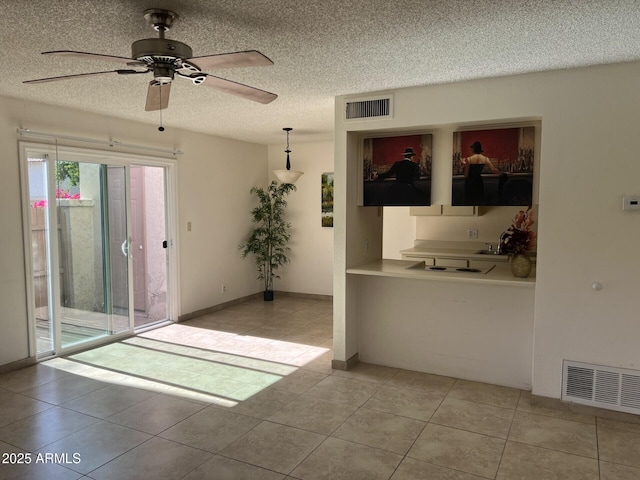 empty room featuring ceiling fan, a textured ceiling, and light tile patterned floors