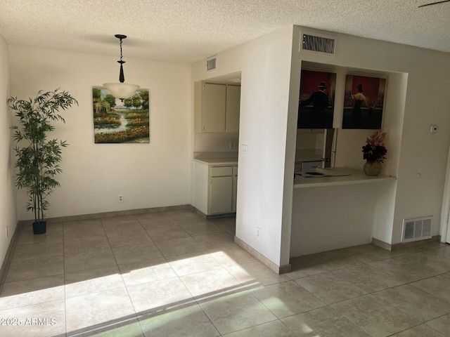 tiled empty room featuring a textured ceiling