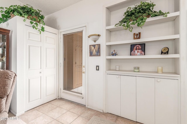 interior space with light tile patterned floors, built in features, and a textured ceiling