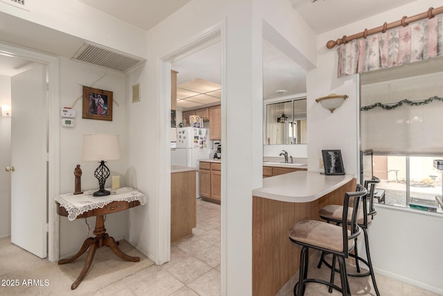 kitchen featuring light countertops, a kitchen breakfast bar, visible vents, and a sink