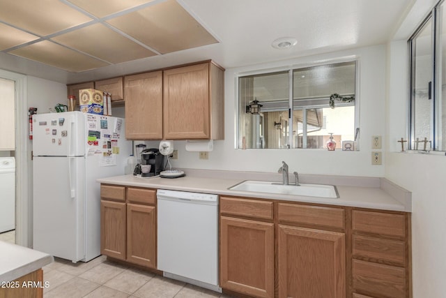 kitchen with light countertops, light tile patterned flooring, white appliances, washer / clothes dryer, and a sink