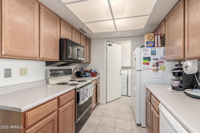 kitchen with white appliances, light tile patterned floors, visible vents, light countertops, and washing machine and dryer