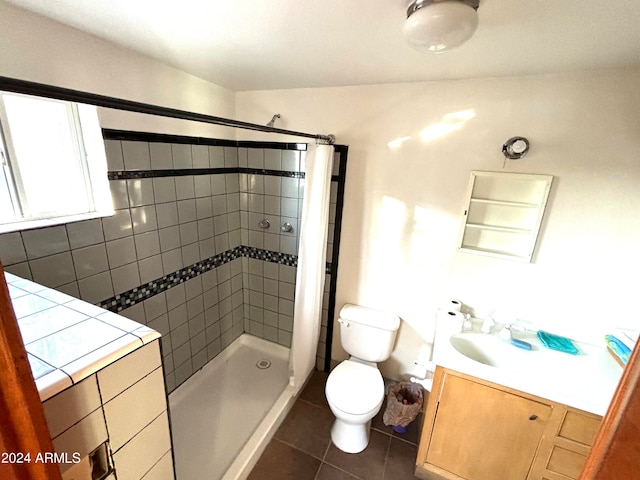 bathroom with a tile shower, tile floors, toilet, and vanity