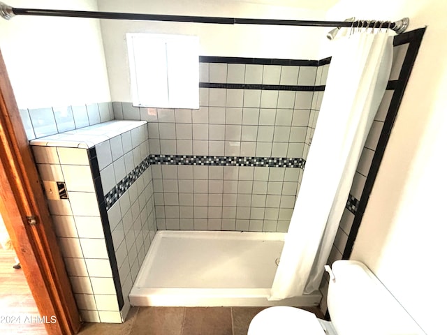 bathroom featuring a shower with curtain, tile flooring, and toilet