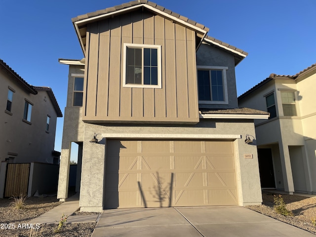 view of front of house with a garage, a tile roof, concrete driveway, and stucco siding