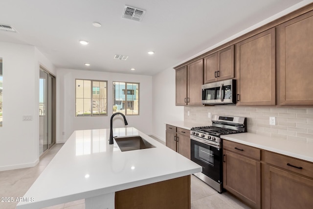 kitchen with backsplash, visible vents, stainless steel appliances, and a sink