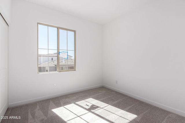 carpeted spare room featuring baseboards