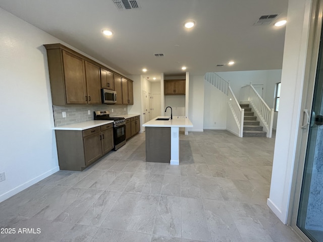 kitchen featuring stainless steel appliances, tasteful backsplash, sink, and a kitchen island with sink