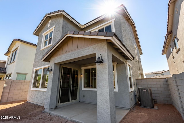 back of house featuring central air condition unit, fence, stucco siding, board and batten siding, and a patio area