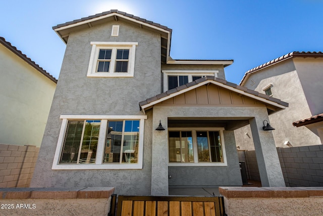 view of front of house featuring a tile roof, fence, and stucco siding