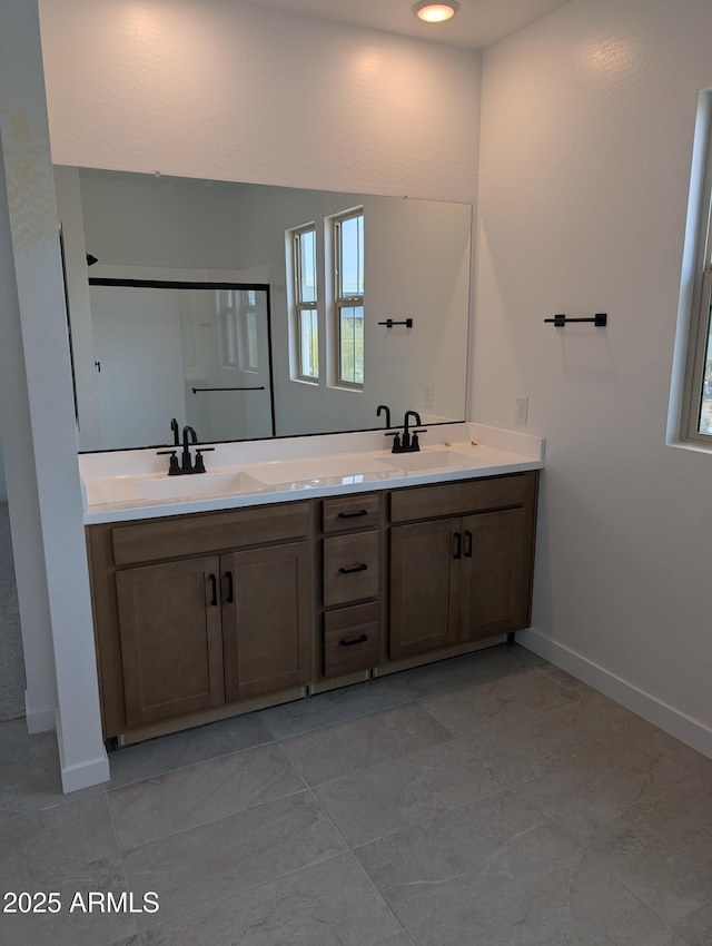 full bath featuring double vanity, a sink, and baseboards