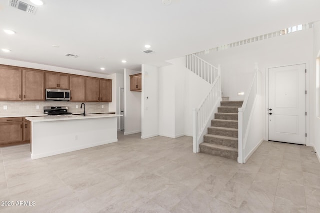 kitchen featuring visible vents, appliances with stainless steel finishes, brown cabinetry, and decorative backsplash