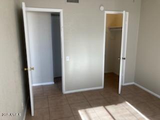 104 N Casa Grande Ave, Casa Grande, AZ 85122 - unfurnished bedroom featuring tile patterned flooring, baseboards, and a spacious closet