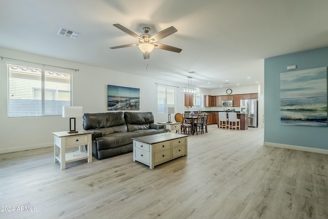 living room with plenty of natural light, light hardwood / wood-style floors, and ceiling fan