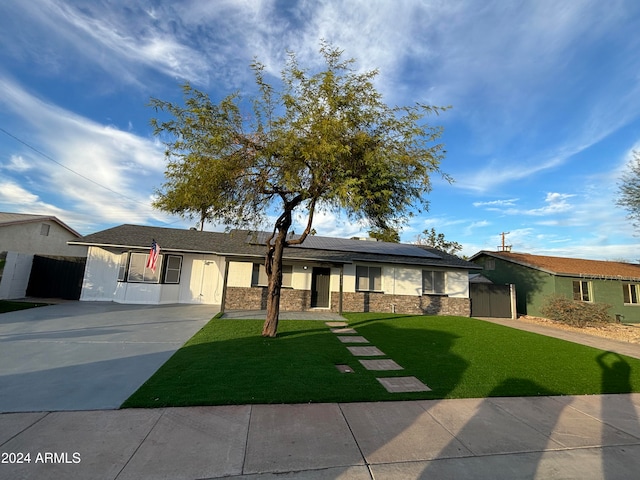 ranch-style home featuring a front lawn and solar panels