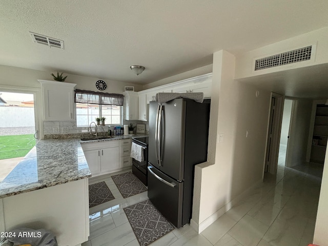 kitchen with white cabinetry, sink, light stone countertops, black range with electric cooktop, and stainless steel fridge