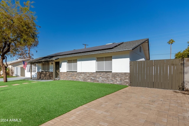 ranch-style house featuring a front yard and solar panels