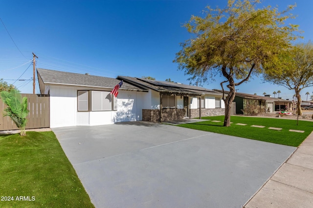 ranch-style house featuring a front lawn and solar panels