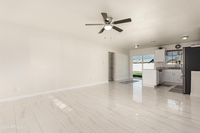 unfurnished living room with ceiling fan and a textured ceiling