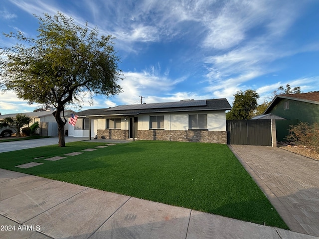 view of front facade featuring solar panels and a front yard