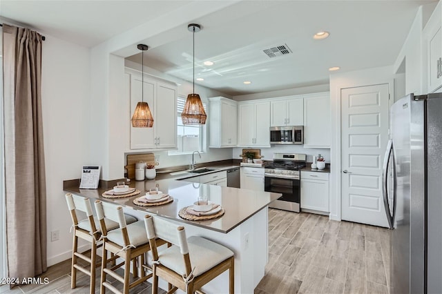 kitchen featuring stainless steel appliances, decorative light fixtures, kitchen peninsula, and white cabinets