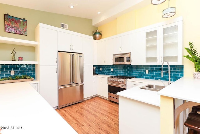 kitchen featuring sink, high end appliances, decorative backsplash, and white cabinetry