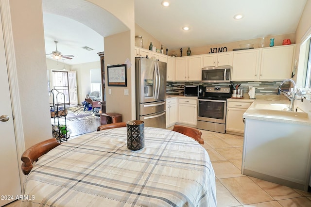 kitchen with ceiling fan, decorative backsplash, lofted ceiling, and stainless steel appliances