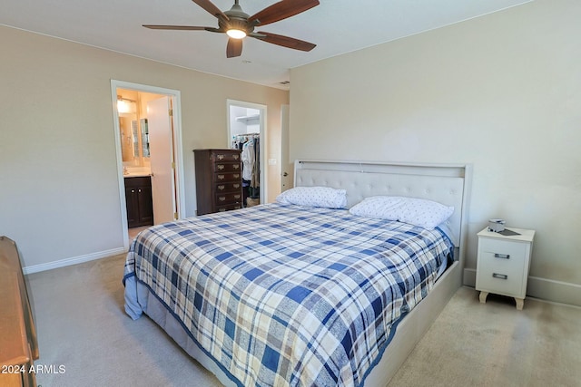 bedroom with a spacious closet, ceiling fan, ensuite bathroom, light carpet, and a closet