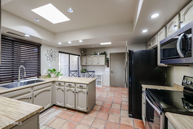 kitchen featuring sink, light tile patterned floors, kitchen peninsula, and appliances with stainless steel finishes