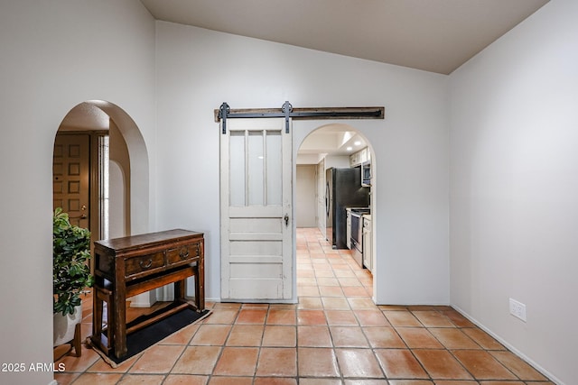 interior space with lofted ceiling, a barn door, and light tile patterned floors