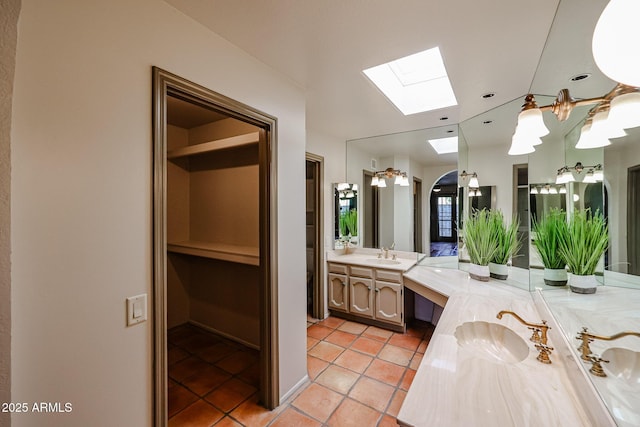 bathroom with vanity, a skylight, and tile patterned floors