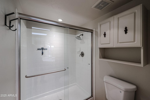 bathroom featuring a shower with door and toilet