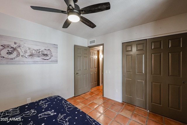 unfurnished bedroom with tile patterned flooring, ceiling fan, and a closet