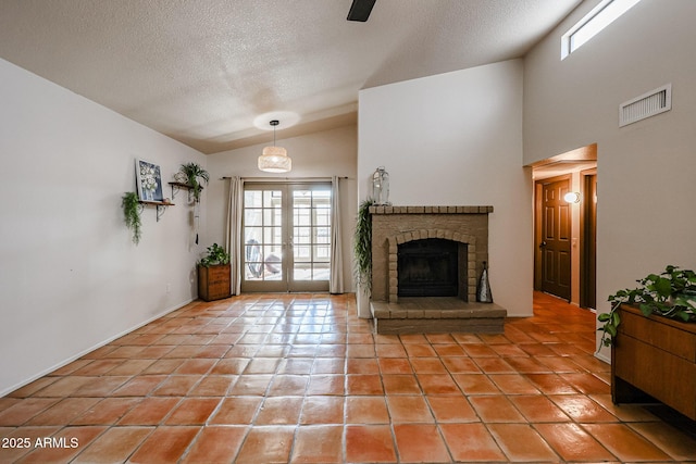 unfurnished living room featuring lofted ceiling, light tile patterned floors, a brick fireplace, a textured ceiling, and french doors