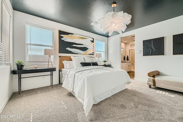 bedroom with carpet flooring, ensuite bath, a textured ceiling, and multiple windows