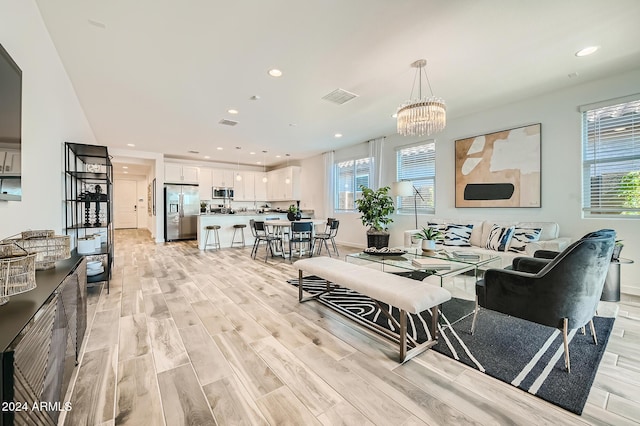 living room with a chandelier, light wood-type flooring, and a healthy amount of sunlight