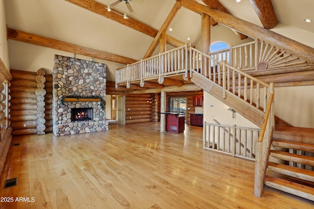 unfurnished living room with beamed ceiling, high vaulted ceiling, visible vents, and log walls
